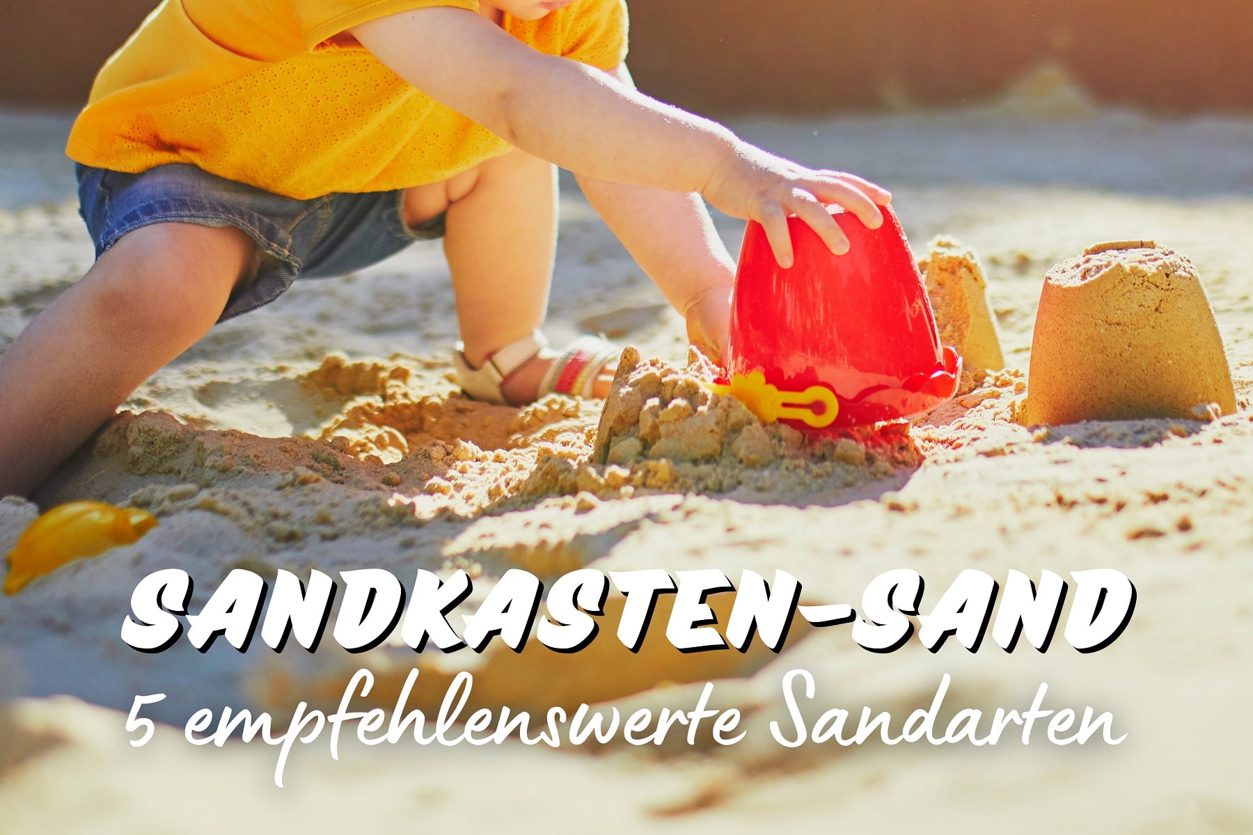 Kind spielt in Sandkasten mit Sand
